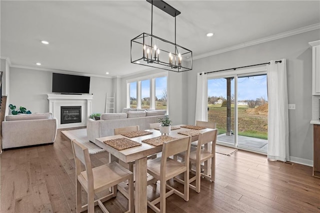 dining space featuring hardwood / wood-style flooring, ornamental molding, and an inviting chandelier