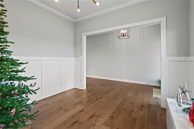 unfurnished dining area with dark hardwood / wood-style flooring, ornamental molding, and an inviting chandelier