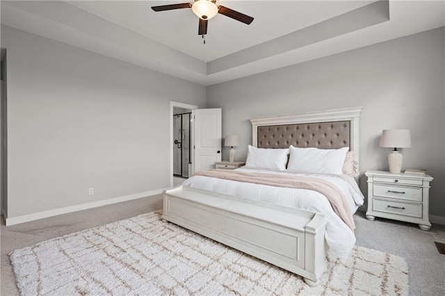 bedroom with light colored carpet, a raised ceiling, and ceiling fan