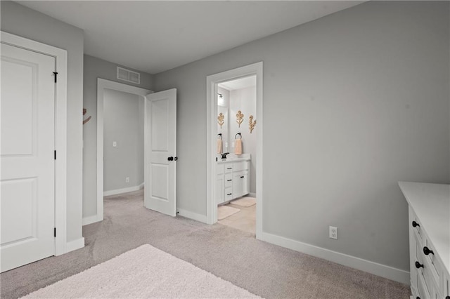 bedroom with connected bathroom and light colored carpet