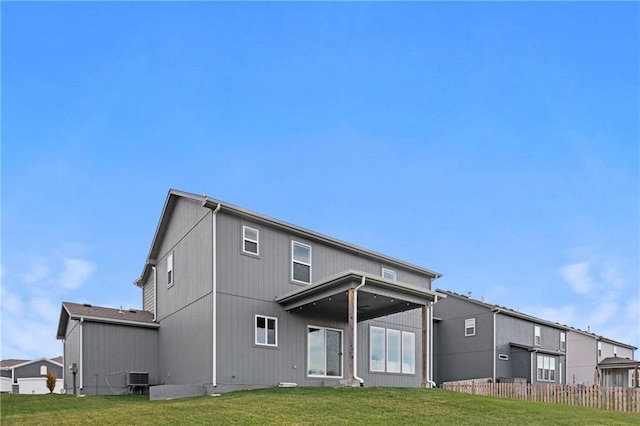 rear view of property with central AC and a lawn