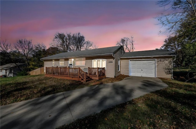 ranch-style home featuring a yard, a deck, and a garage