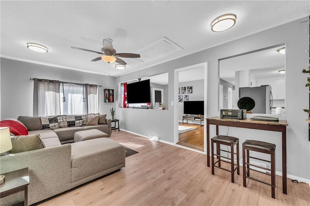 living room featuring a textured ceiling, light wood-type flooring, ceiling fan, and ornamental molding