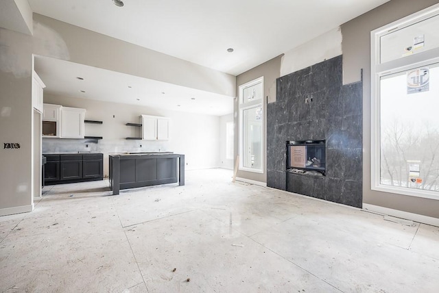 unfurnished living room with a tiled fireplace and a healthy amount of sunlight