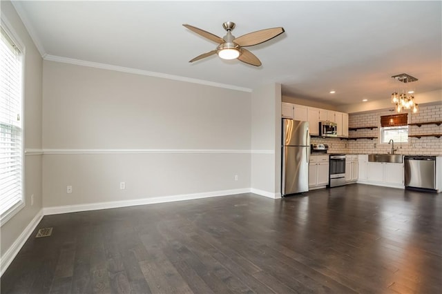 unfurnished living room with ceiling fan with notable chandelier, dark hardwood / wood-style flooring, ornamental molding, and sink