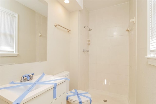 bathroom featuring a tile shower, vanity, and toilet