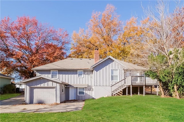 rear view of property with a garage, a yard, and a wooden deck