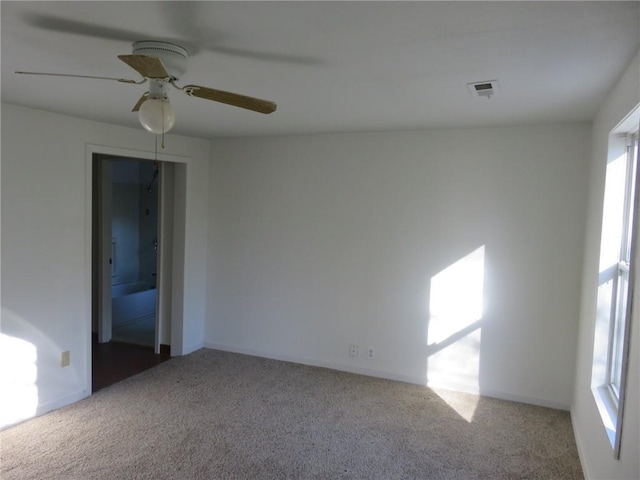 carpeted empty room featuring ceiling fan and a wealth of natural light