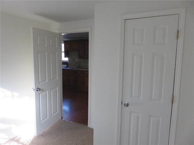 hall featuring light colored carpet and sink