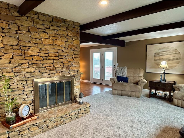 unfurnished living room with beamed ceiling, a textured ceiling, carpet flooring, and a stone fireplace