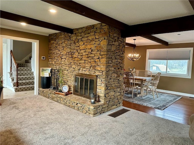 unfurnished living room featuring hardwood / wood-style flooring, a fireplace, beamed ceiling, and an inviting chandelier