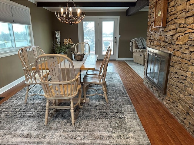 dining room with hardwood / wood-style floors, a fireplace, beamed ceiling, and a chandelier