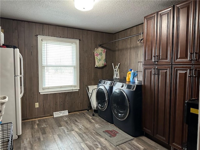 laundry room featuring washer and dryer, wood walls, cabinets, and dark hardwood / wood-style floors