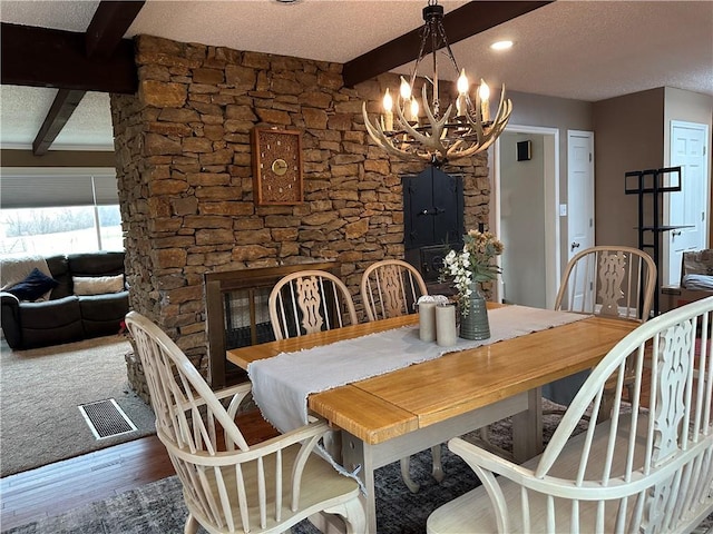 dining space with beam ceiling, wood-type flooring, a textured ceiling, and a chandelier