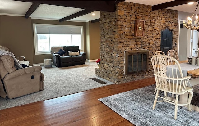 living room featuring beam ceiling, carpet flooring, an inviting chandelier, a textured ceiling, and a fireplace