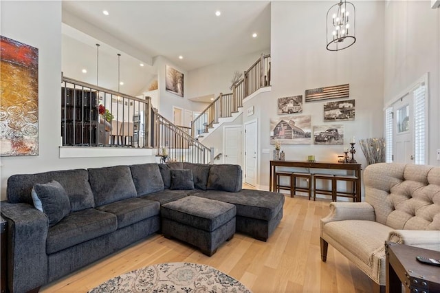 living room featuring wood-type flooring, a towering ceiling, and a notable chandelier