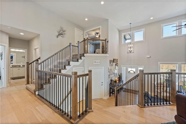 stairway with ceiling fan, wood-type flooring, and a high ceiling