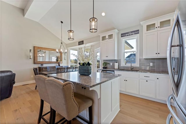 kitchen with stainless steel refrigerator, white cabinetry, a healthy amount of sunlight, and light hardwood / wood-style floors