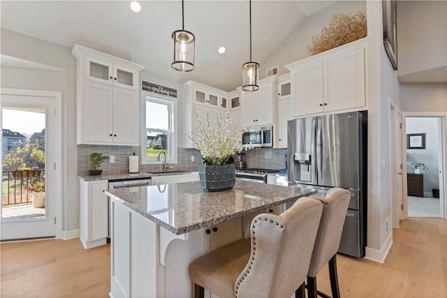 kitchen with a wealth of natural light, white cabinetry, a center island, and stainless steel appliances