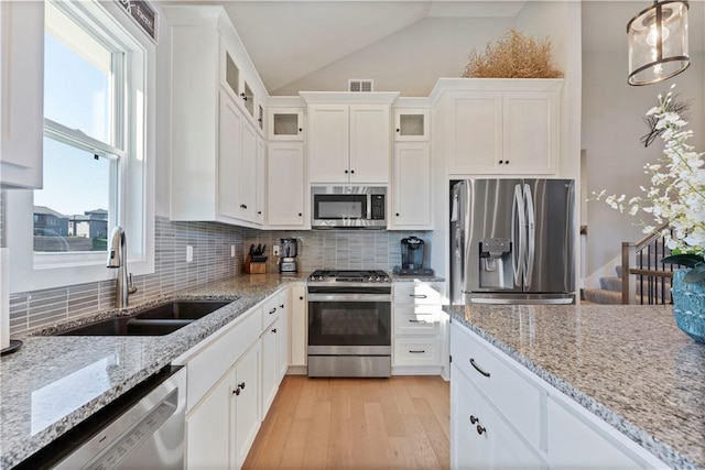 kitchen featuring stainless steel appliances, sink, light hardwood / wood-style floors, white cabinetry, and lofted ceiling