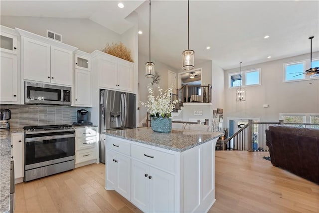 kitchen with white cabinets, appliances with stainless steel finishes, and hanging light fixtures