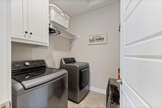 clothes washing area featuring washing machine and dryer and cabinets