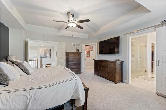 bedroom with a raised ceiling, ensuite bath, ceiling fan, and light colored carpet