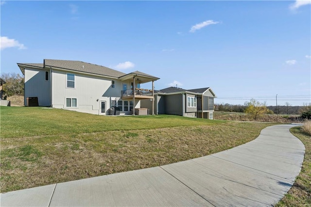 rear view of house with a balcony and a lawn