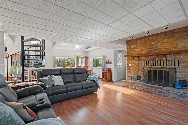 living room featuring hardwood / wood-style floors, a paneled ceiling, and a stone fireplace