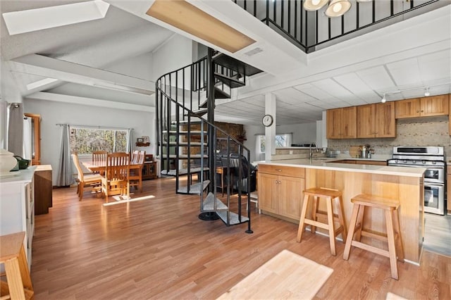 kitchen with kitchen peninsula, decorative backsplash, track lighting, double oven range, and light hardwood / wood-style floors