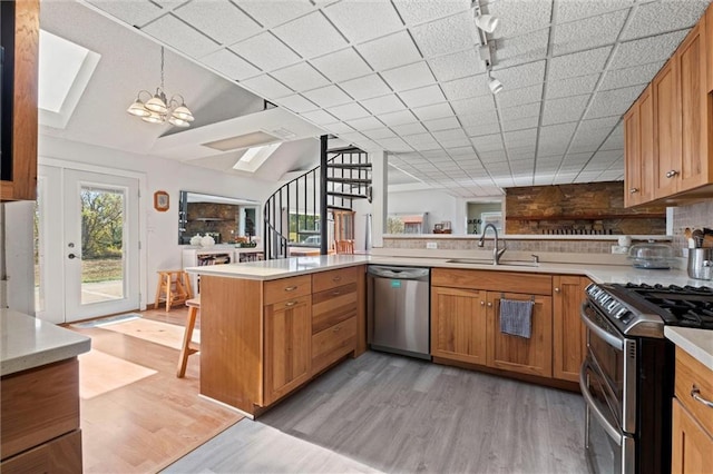 kitchen featuring track lighting, sink, a skylight, kitchen peninsula, and stainless steel appliances