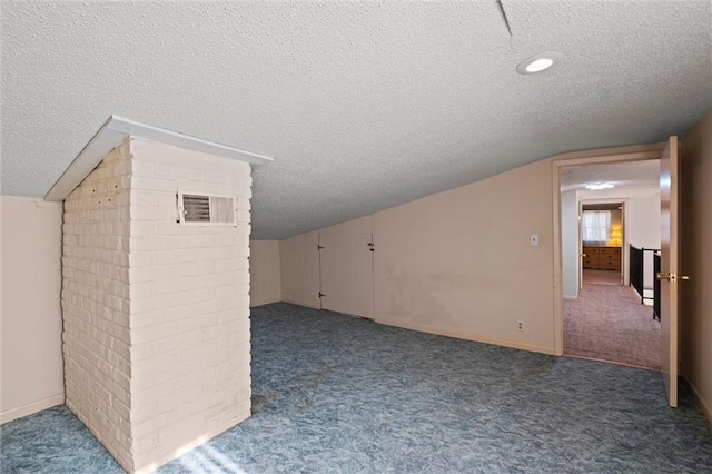 additional living space featuring dark carpet, lofted ceiling, and a textured ceiling