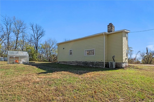 view of side of home with a lawn, central AC, and an outbuilding