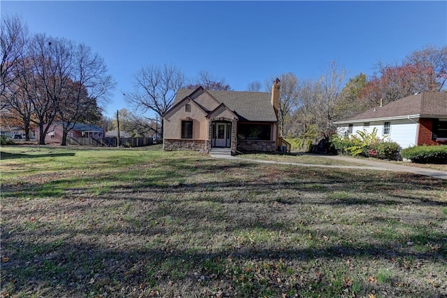 view of front of property with stone siding, a chimney, and a front lawn