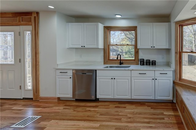 kitchen with a sink, visible vents, white cabinets, light wood-type flooring, and dishwasher