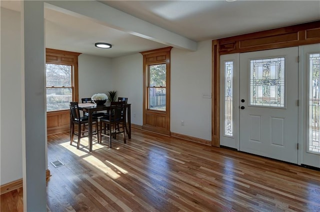 foyer with visible vents, wood finished floors, and beamed ceiling