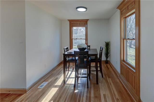 dining area with visible vents, plenty of natural light, baseboards, and wood finished floors