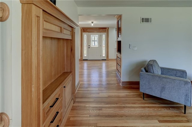 foyer entrance featuring light wood finished floors, visible vents, and baseboards