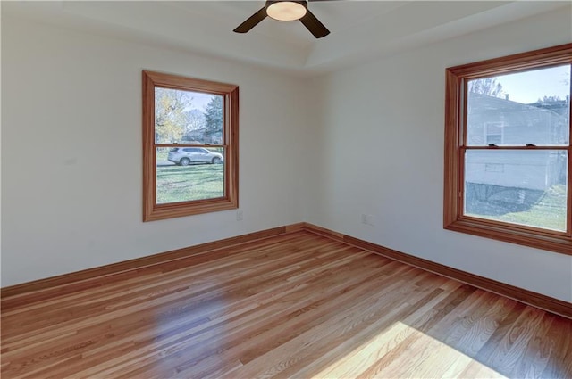 empty room featuring light wood finished floors, a ceiling fan, and baseboards