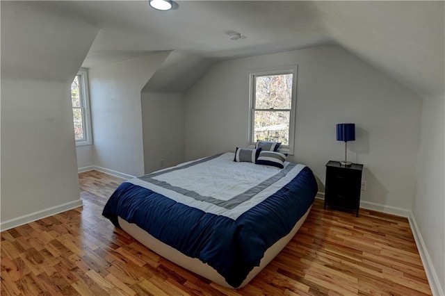 bedroom featuring baseboards, vaulted ceiling, and wood finished floors