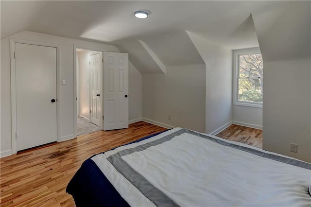 unfurnished bedroom featuring vaulted ceiling, baseboards, and wood finished floors