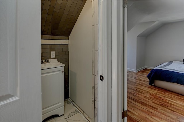 interior space with lofted ceiling, vanity, and wood finished floors