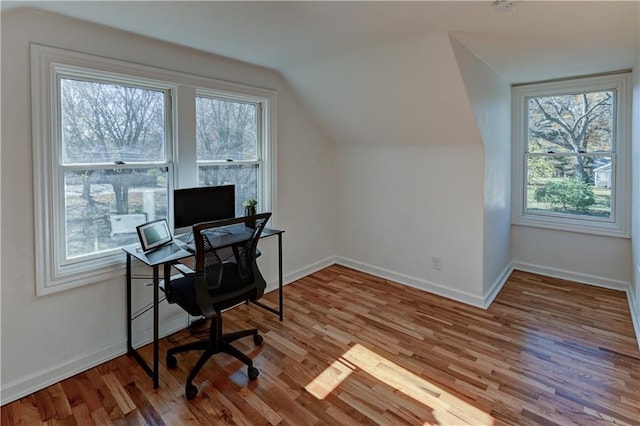 home office featuring a healthy amount of sunlight, baseboards, wood finished floors, and lofted ceiling