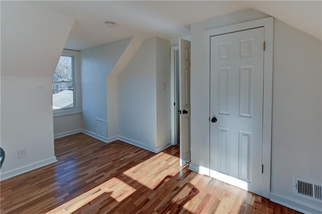 bonus room featuring baseboards, visible vents, vaulted ceiling, and wood finished floors