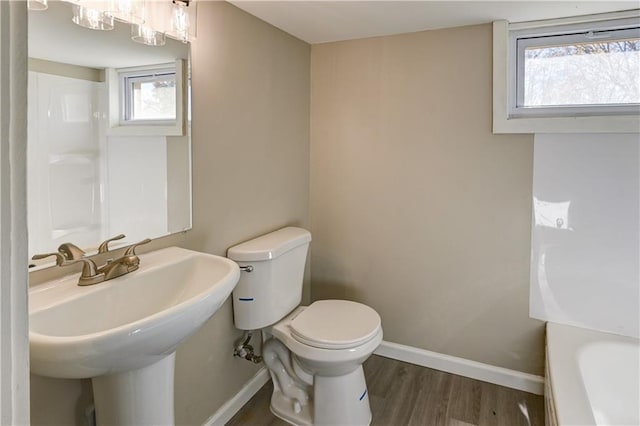 full bath featuring toilet, a bathtub, baseboards, and wood finished floors