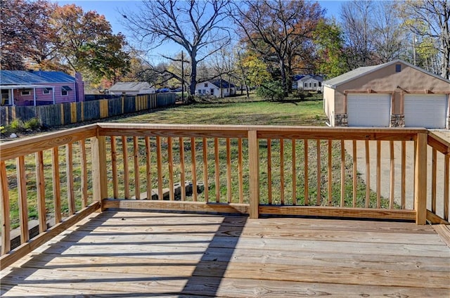 deck featuring a detached garage, an outdoor structure, fence, a lawn, and a residential view