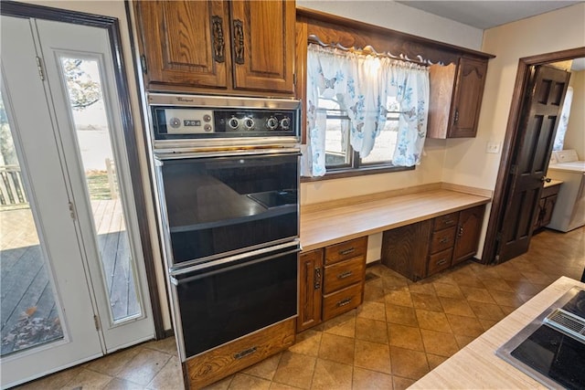 kitchen with washer / dryer, double oven, and light tile patterned flooring