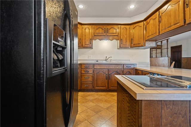 kitchen featuring kitchen peninsula, wooden counters, sink, black appliances, and light tile patterned flooring