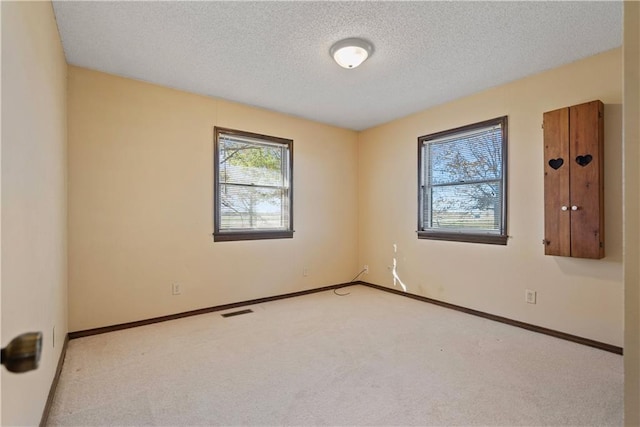 carpeted empty room featuring a textured ceiling