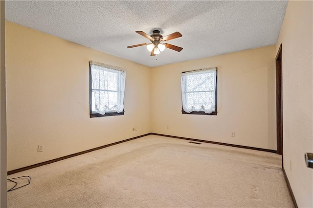 carpeted empty room with ceiling fan, a healthy amount of sunlight, and a textured ceiling